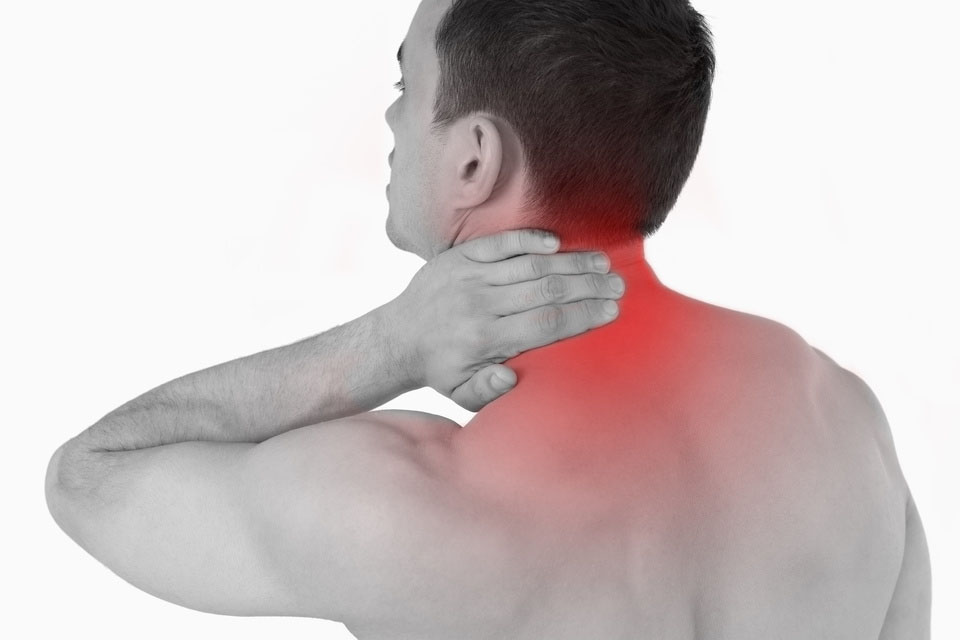 Young man experiencing neck pain against a white background